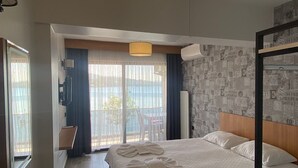 Une chambre d’hôtel comprenant un lit, un bureau, une chaise, un balcon avec vue et un grand luminaire suspendu.