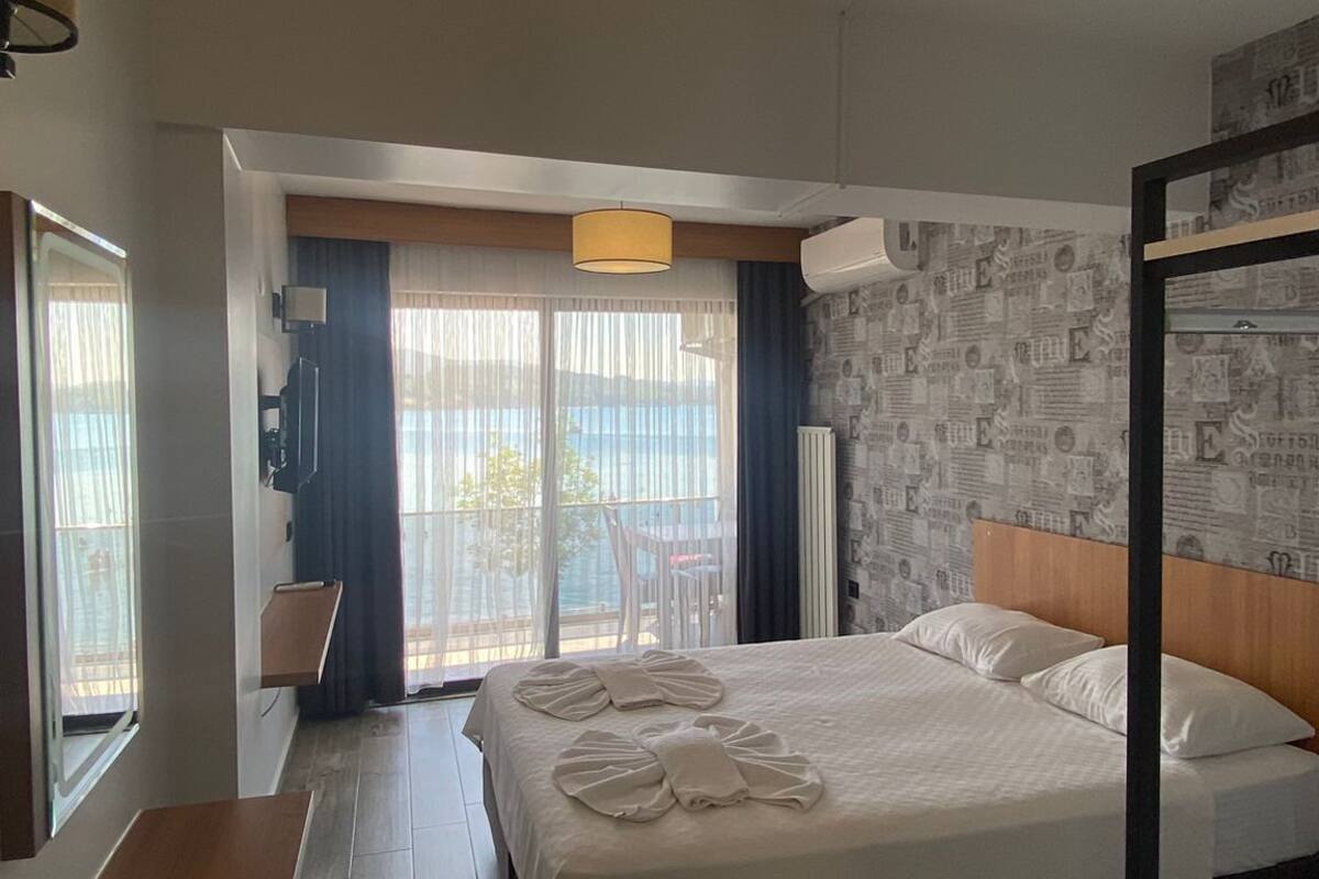 Une chambre d’hôtel comprenant un lit, un bureau, une chaise, un balcon avec vue et un grand luminaire suspendu.