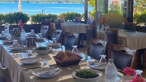 Un espace de restauration en plein air avec des tables disposées pour deux personnes, offrant une vue sur un plan d’eau.