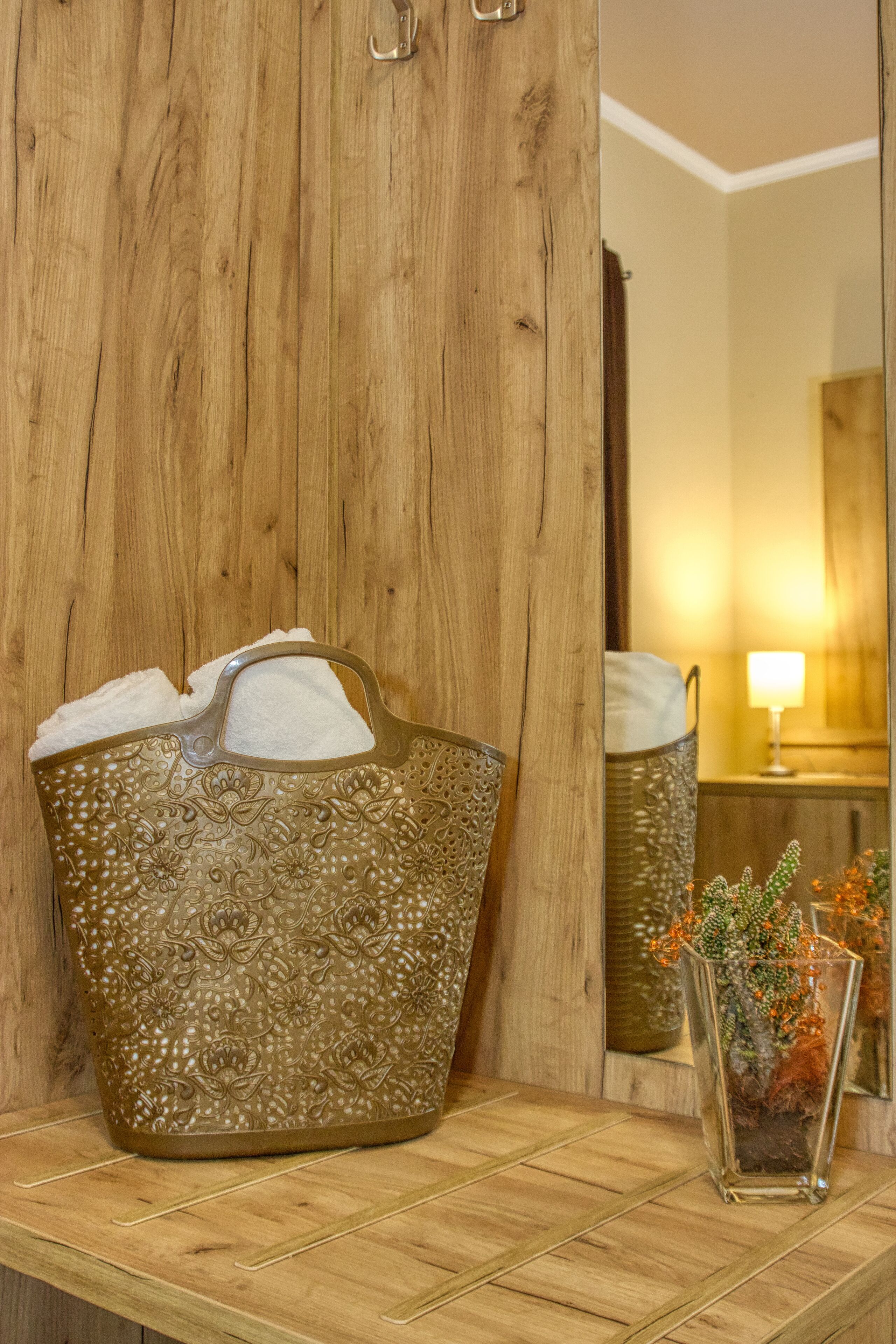 Eine Holzwand mit einem großen Zierkorb und einer kleinen Vase mit Trockenpflanzen.