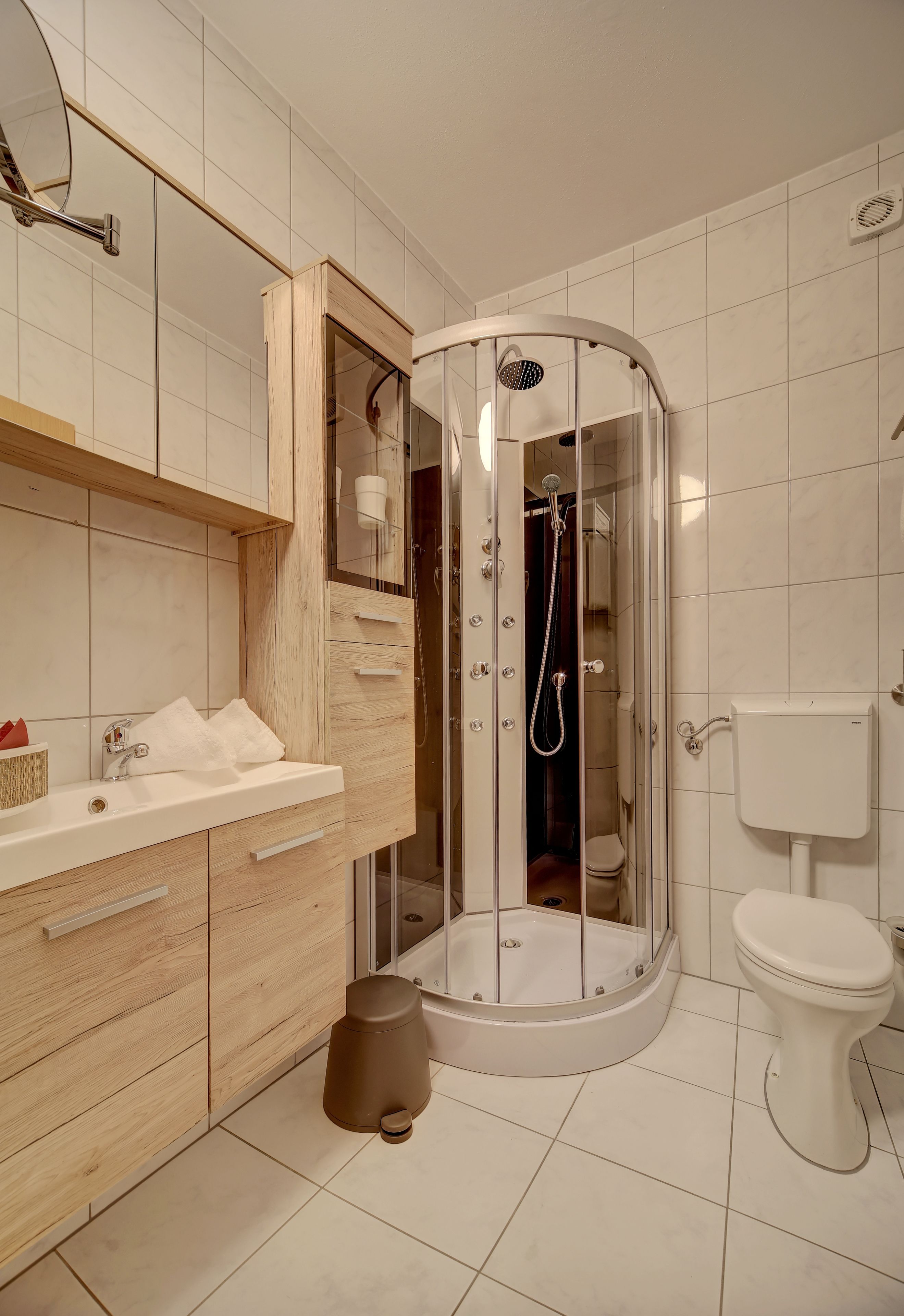 A modern bathroom with a glass-enclosed shower, a white sink, and a toilet.