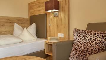 Habitación de hotel con cabecera de madera, mesita de noche con libros, lámpara y almohada de estampado de leopardo.