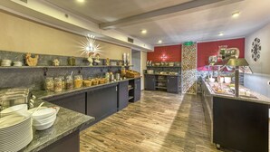 A modern kitchen with granite countertops, a variety of food items, and a red accent wall. - Wellnesshotel Auszeit (Achslach)