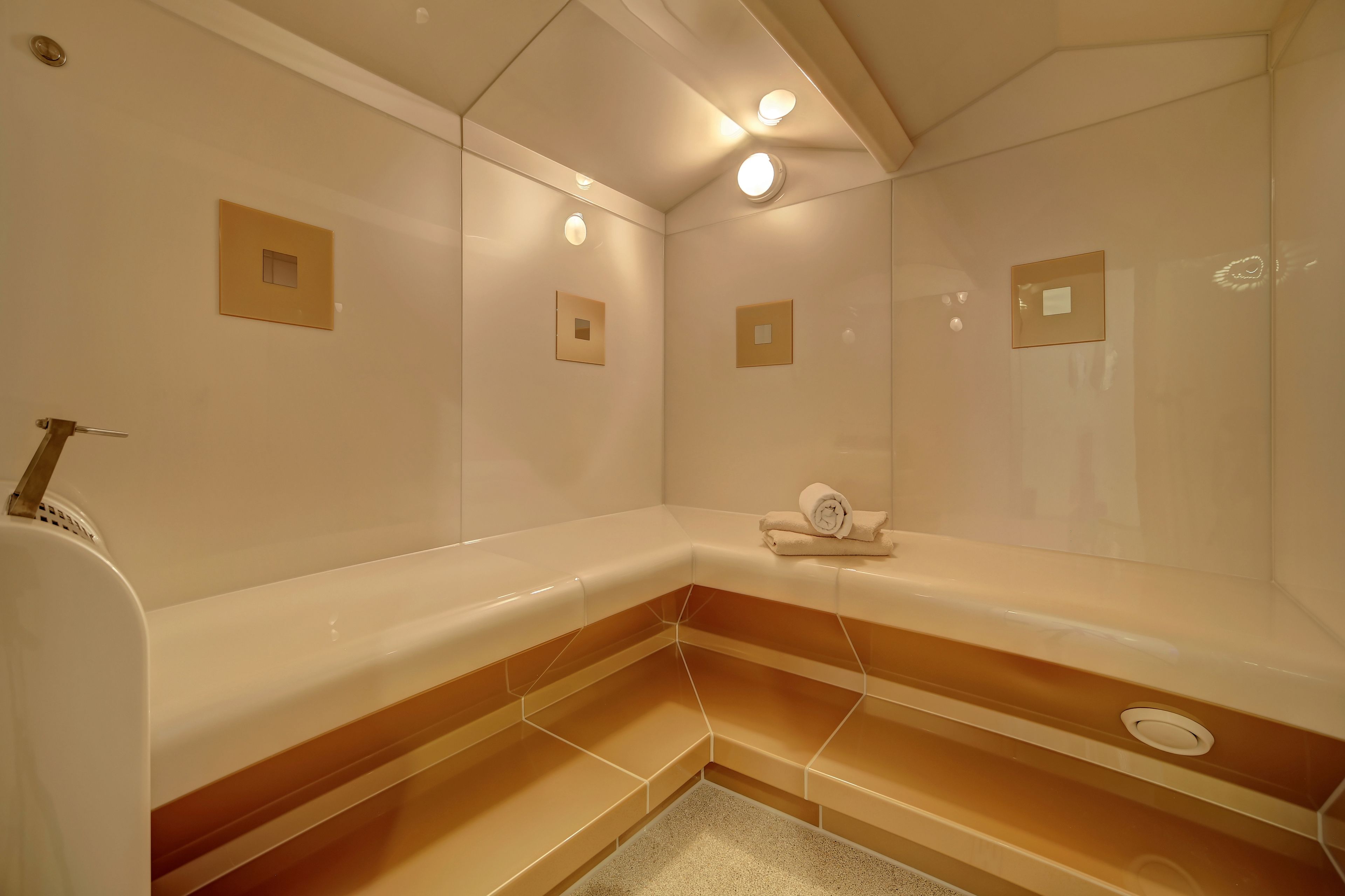 A modern bathroom with a large bathtub, a towel rack, and recessed lighting.