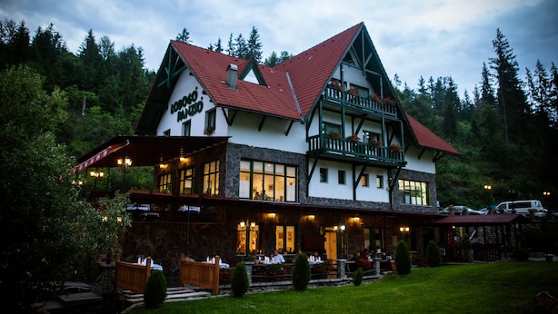 Ein zweistöckiges Gebäude mit einer Stein-Fassade, einem roten Dach und einem Balkon mit Blumenkästen.