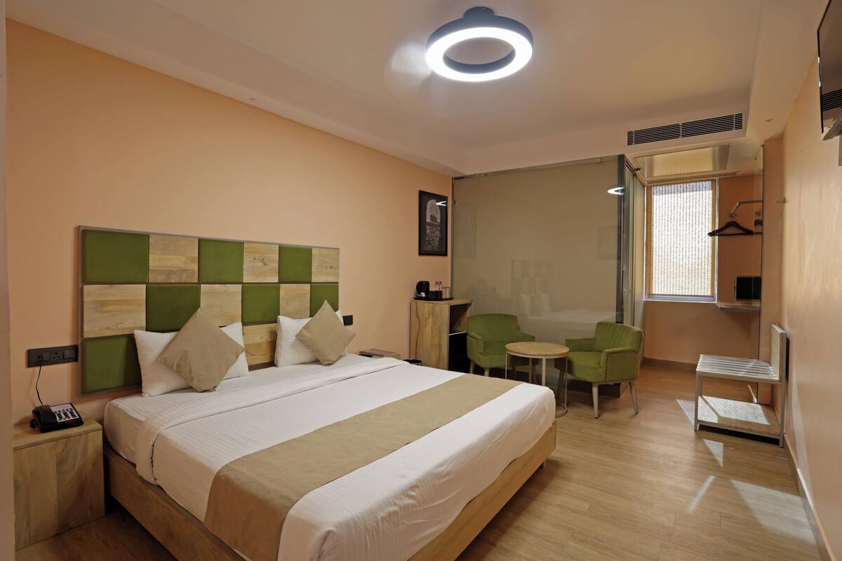 Een hotelkamer met een bed, nachtkastje, stoel en een klein tafeltje.
