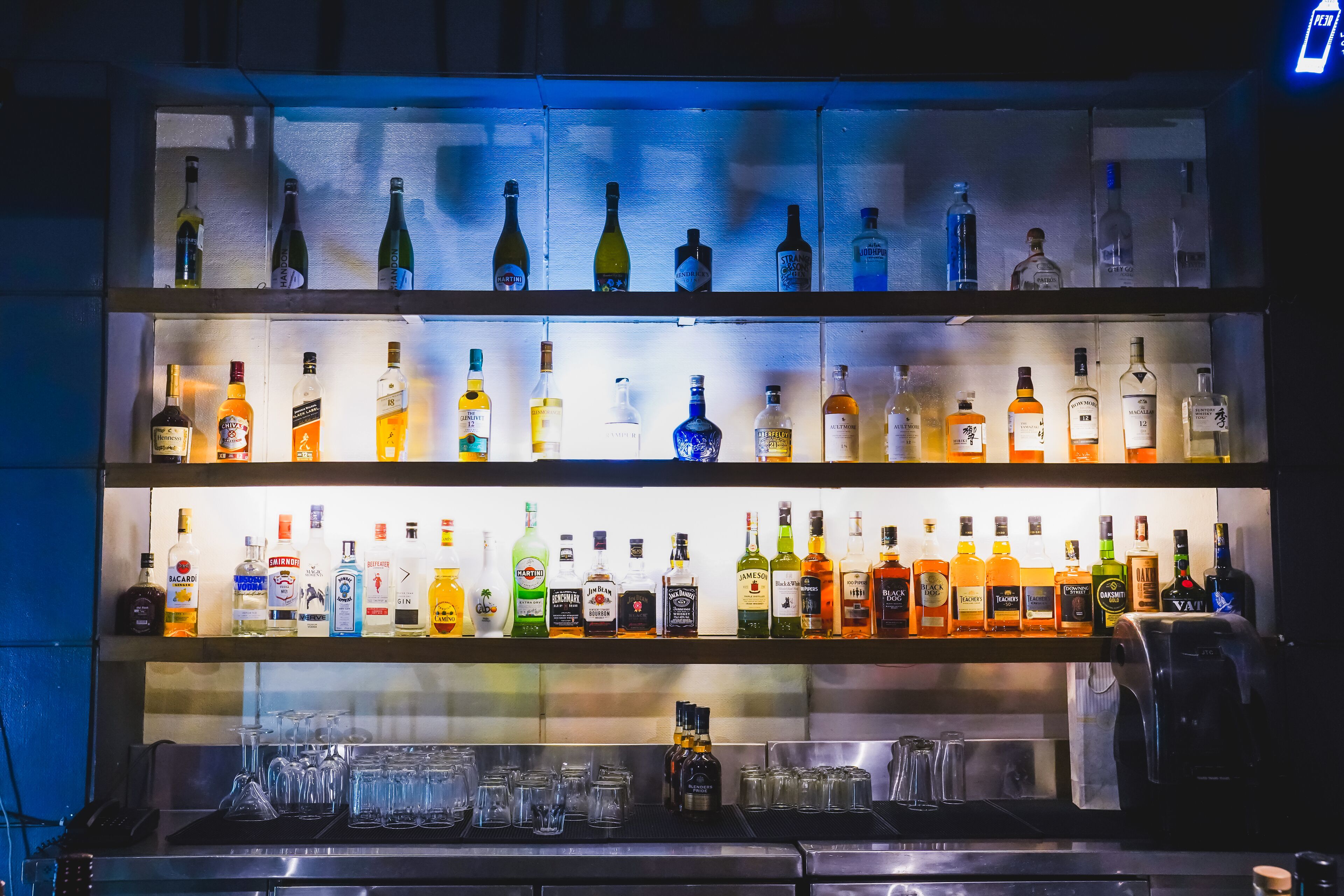Un bar con varias estanterías llenas de botellas de licor y vasos.