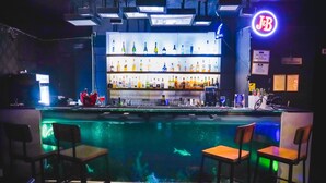 A bar area with a pool, bar stools, and a neon sign. - Hotel Dodas Palace (Jaipur)