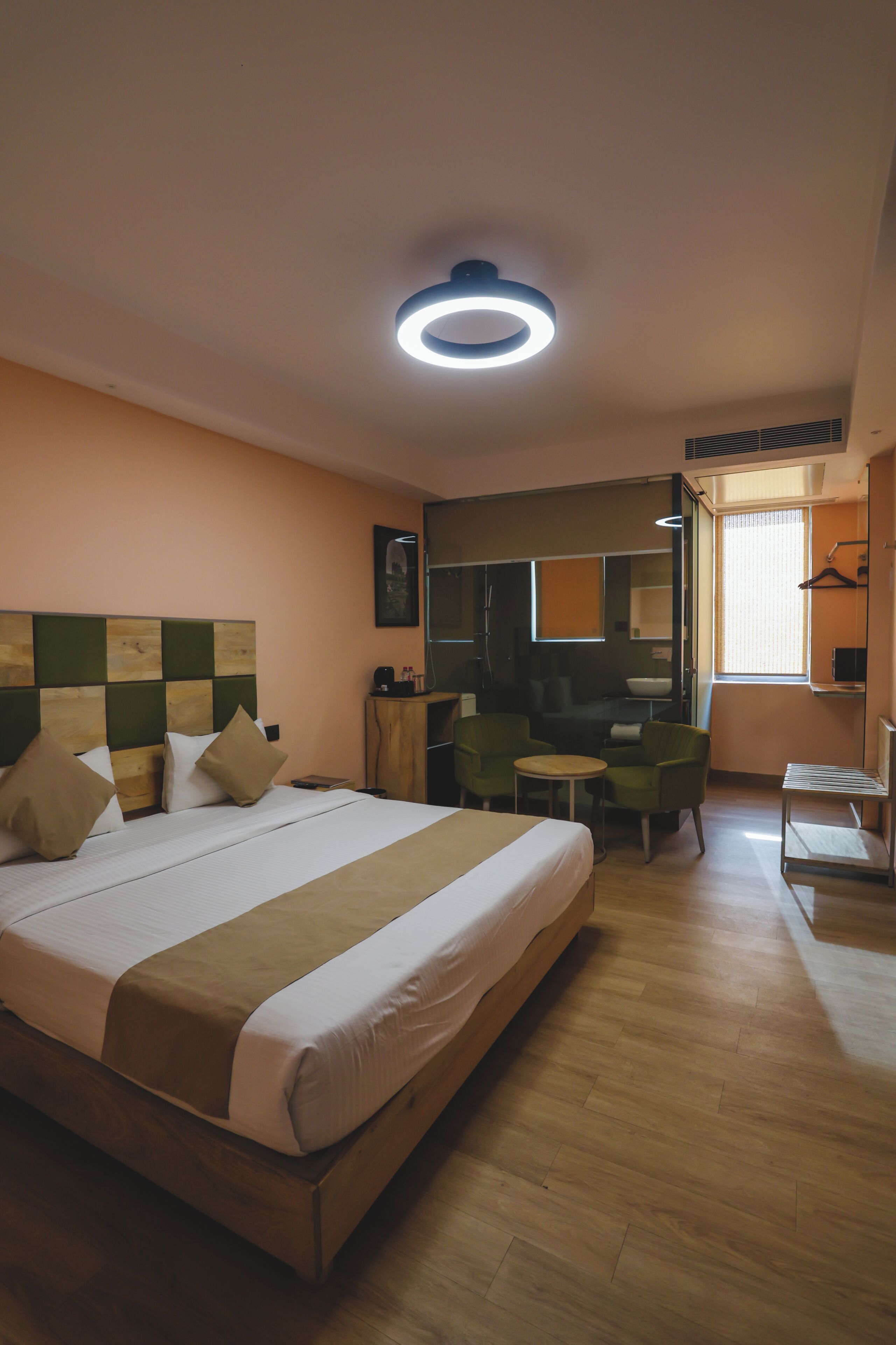 Quarto de hotel com uma cama grande, uma escrivaninha pequena, uma cadeira e um espelho.