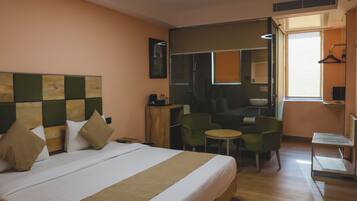 Quarto de hotel com uma cama grande, uma escrivaninha pequena, uma cadeira e um espelho.