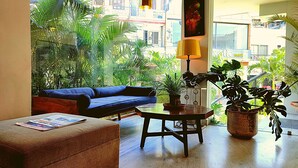 A living room with a blue sofa, a wooden coffee table, and a potted plant. - Hotel Dodas Palace (Jaipur)