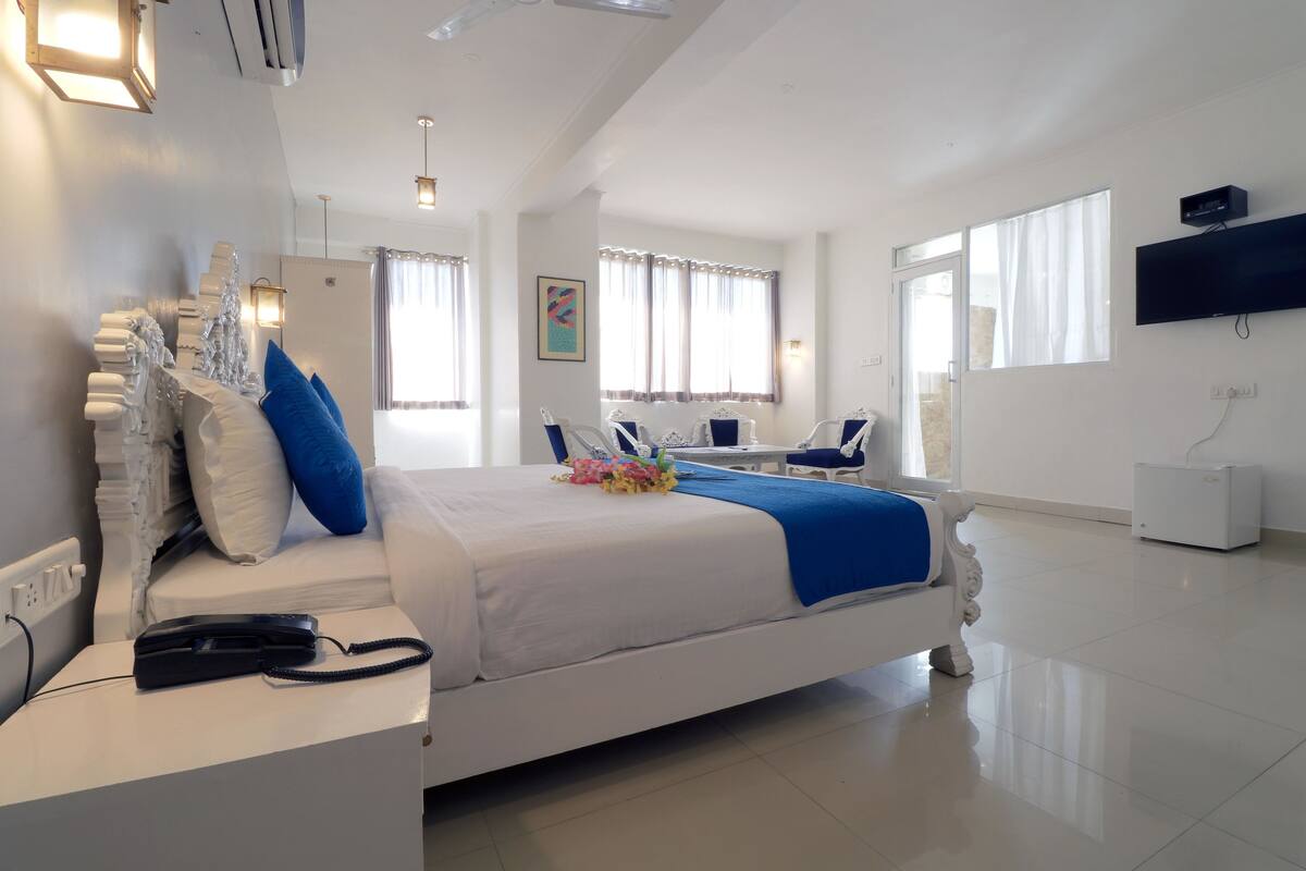 Een moderne hotelkamer met een groot bed, nachtkastjes, een bureau en een flatscreen televisie.