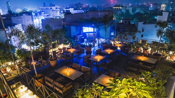 An outdoor terrace with multiple tables and chairs, surrounded by potted plants. - Hotel Dodas Palace (Jaipur)