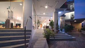 A modern hotel lobby with a wooden staircase, potted plants, and a glass entrance. - Hotel Dodas Palace (Jaipur)