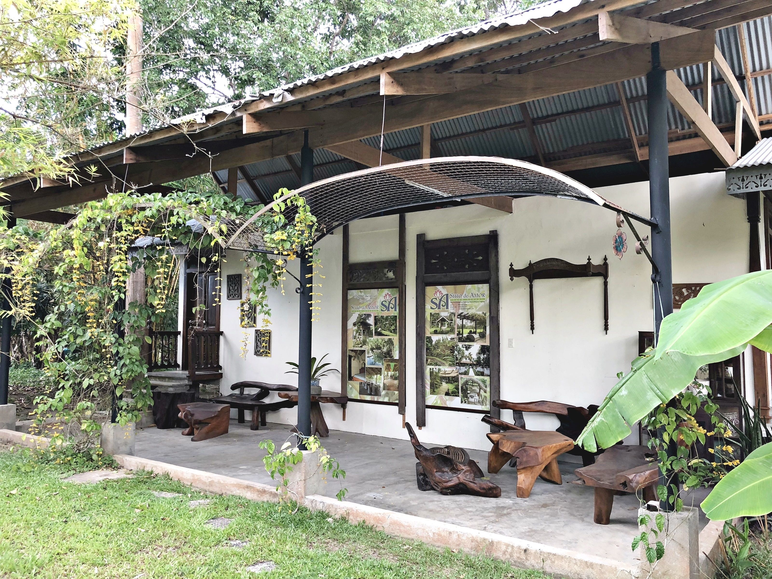 Une structure rustique en bois, dotée d’un porche abrité, de plantes en pot et de meubles en bois.
