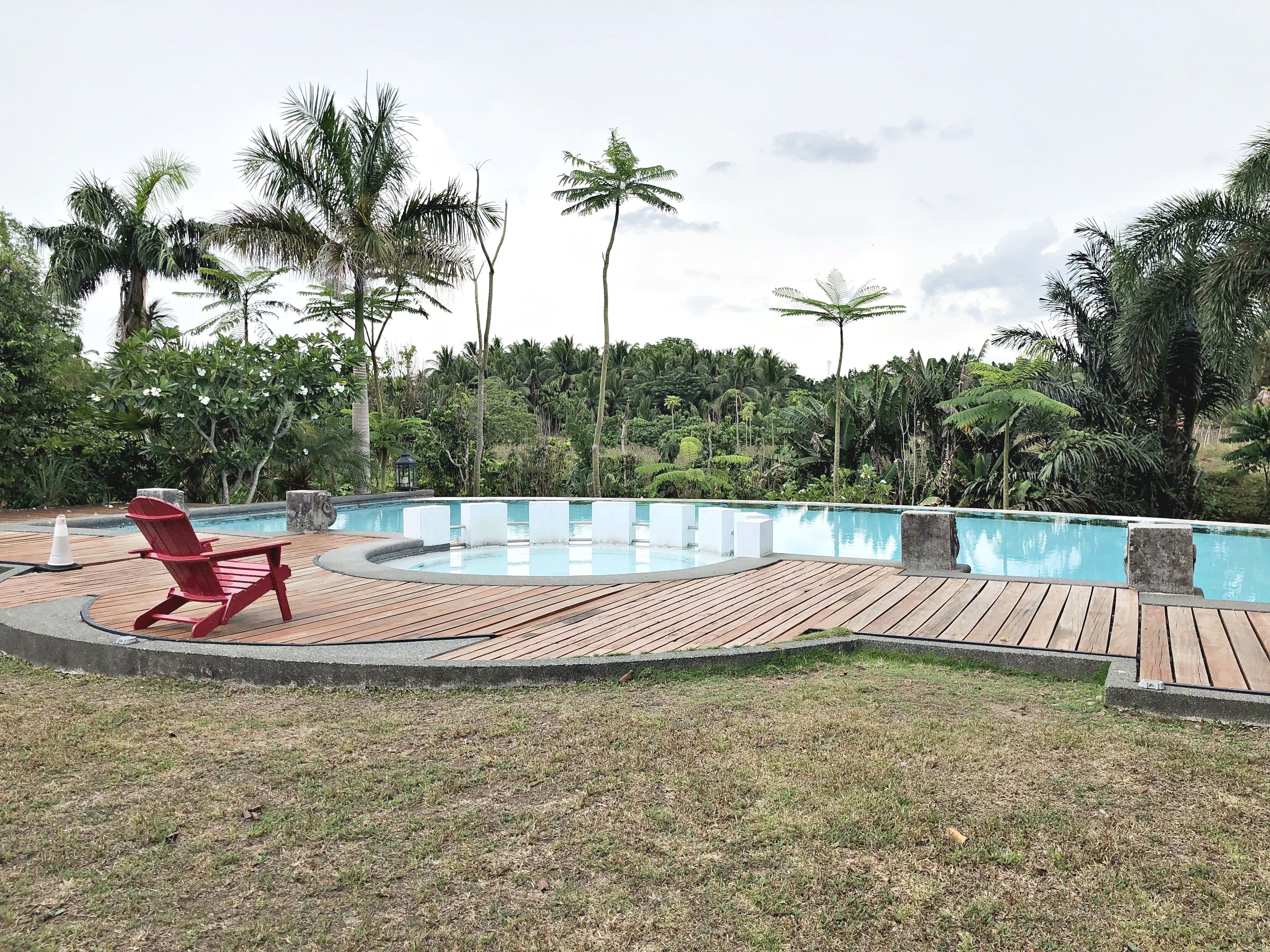 A pool with a wooden deck and a red chair.