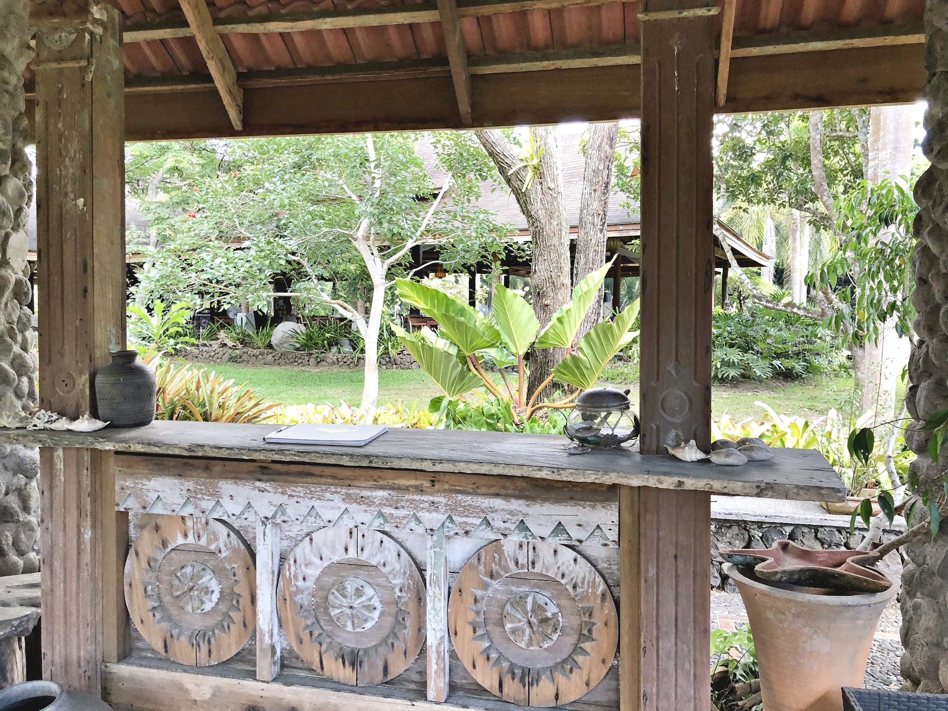 A rustic wooden structure with a view of a garden.