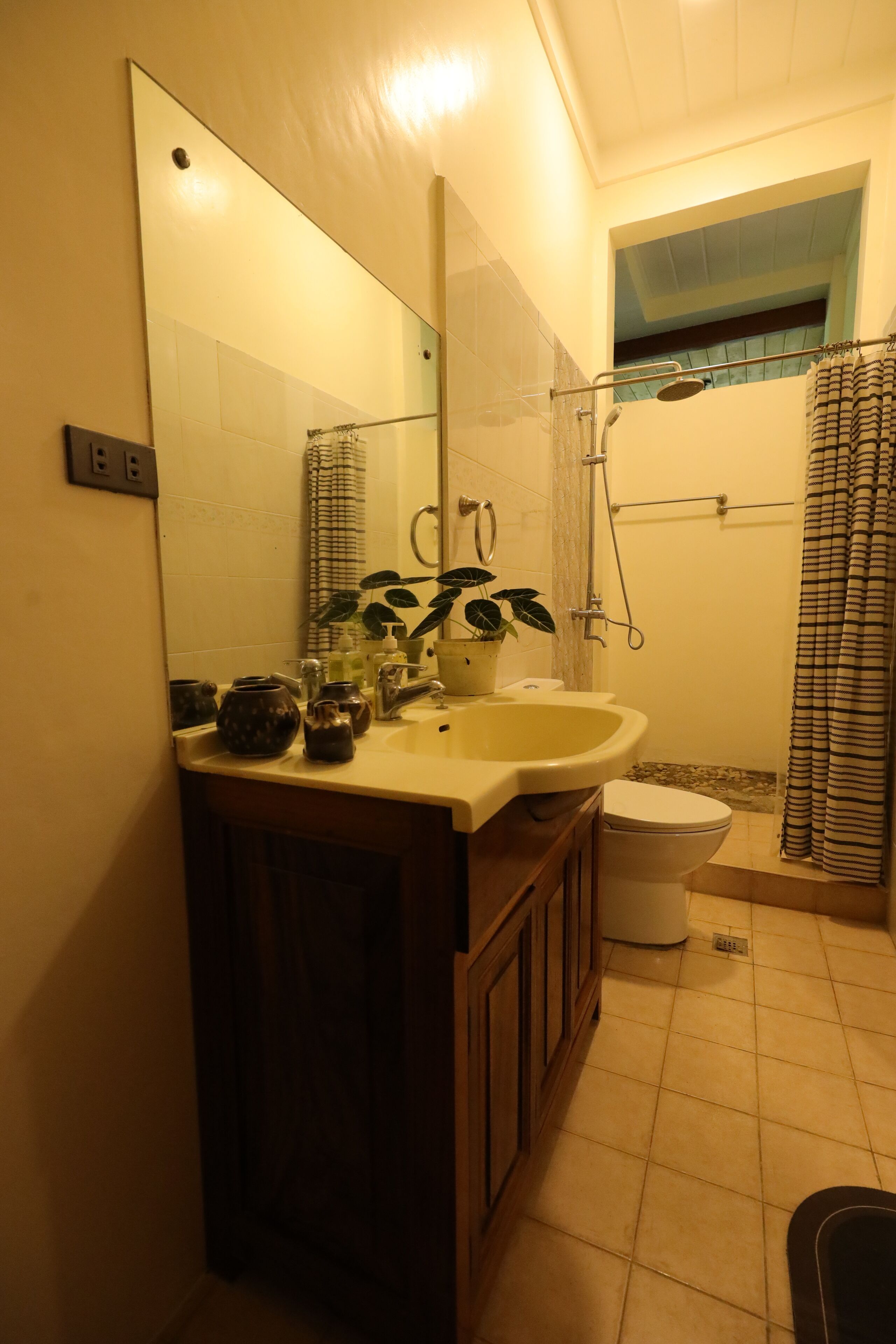 A bathroom with a sink, mirror, and shower.