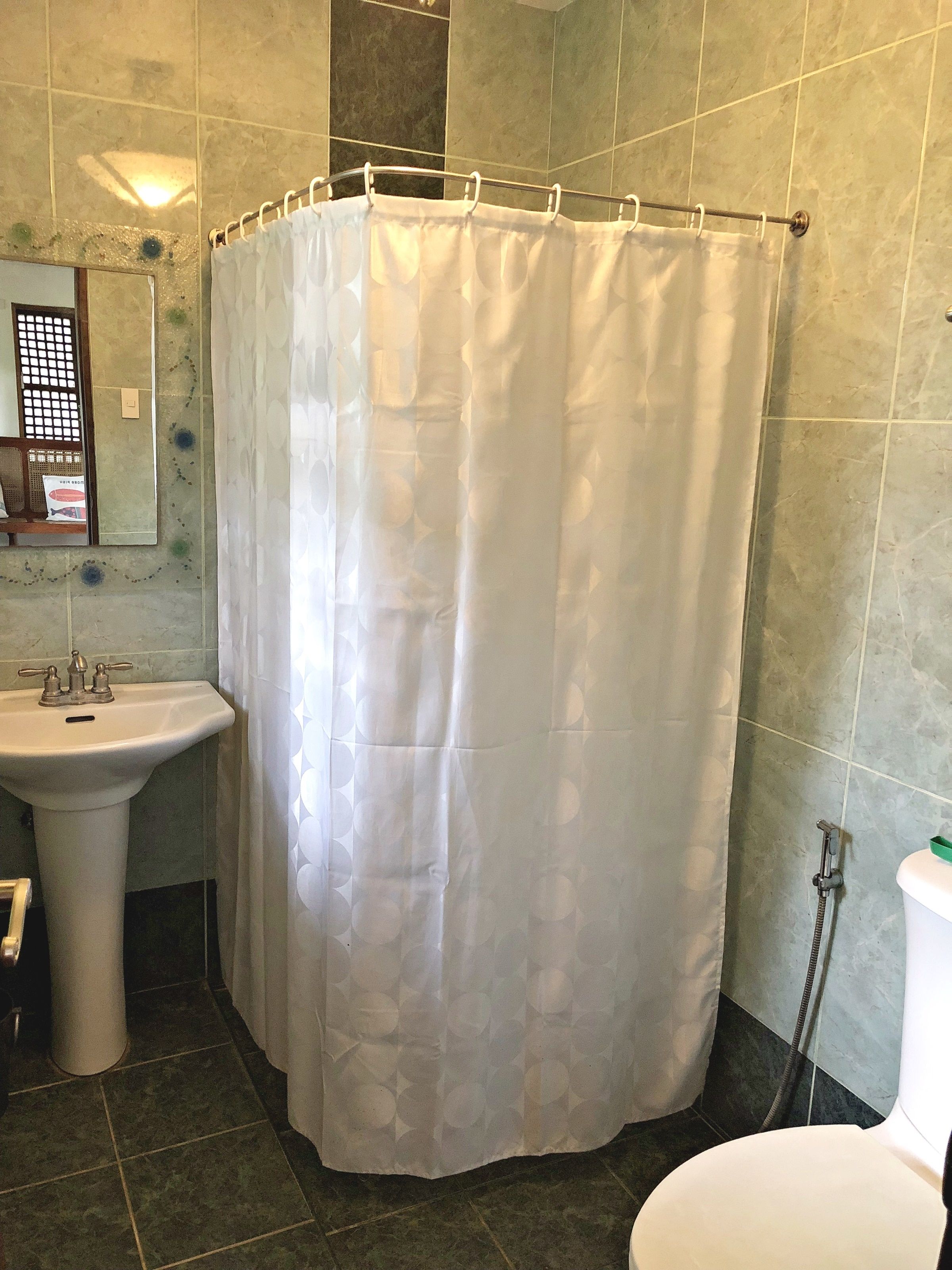 Une salle de bain avec un rideau de douche, un lavabo et des toilettes.