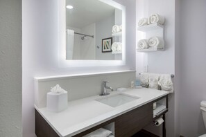 A modern bathroom with a white sink, a mirror, and a towel rack.
