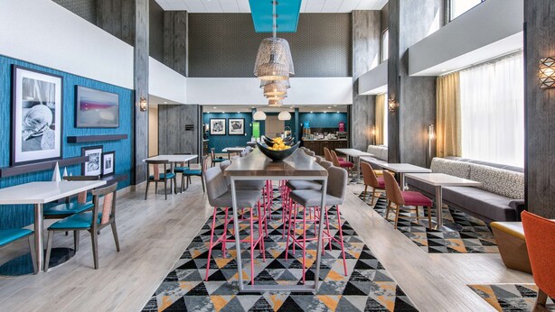 A modern dining area with a central table, multiple seating options, and a geometric patterned rug. - Hampton Inn & Suites Ruidoso Downs (Ruidoso Downs)