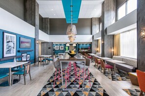 A modern dining area with a central table, multiple seating options, and a geometric patterned rug.