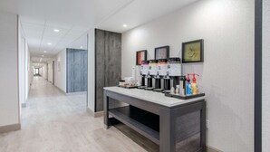 A hotel corridor with a coffee station, framed artwork, and a long hallway. - Hampton Inn & Suites Ruidoso Downs (Ruidoso Downs)