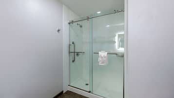 Ducha con cerramiento de vidrio, barra para toallas y una toalla a la vista.