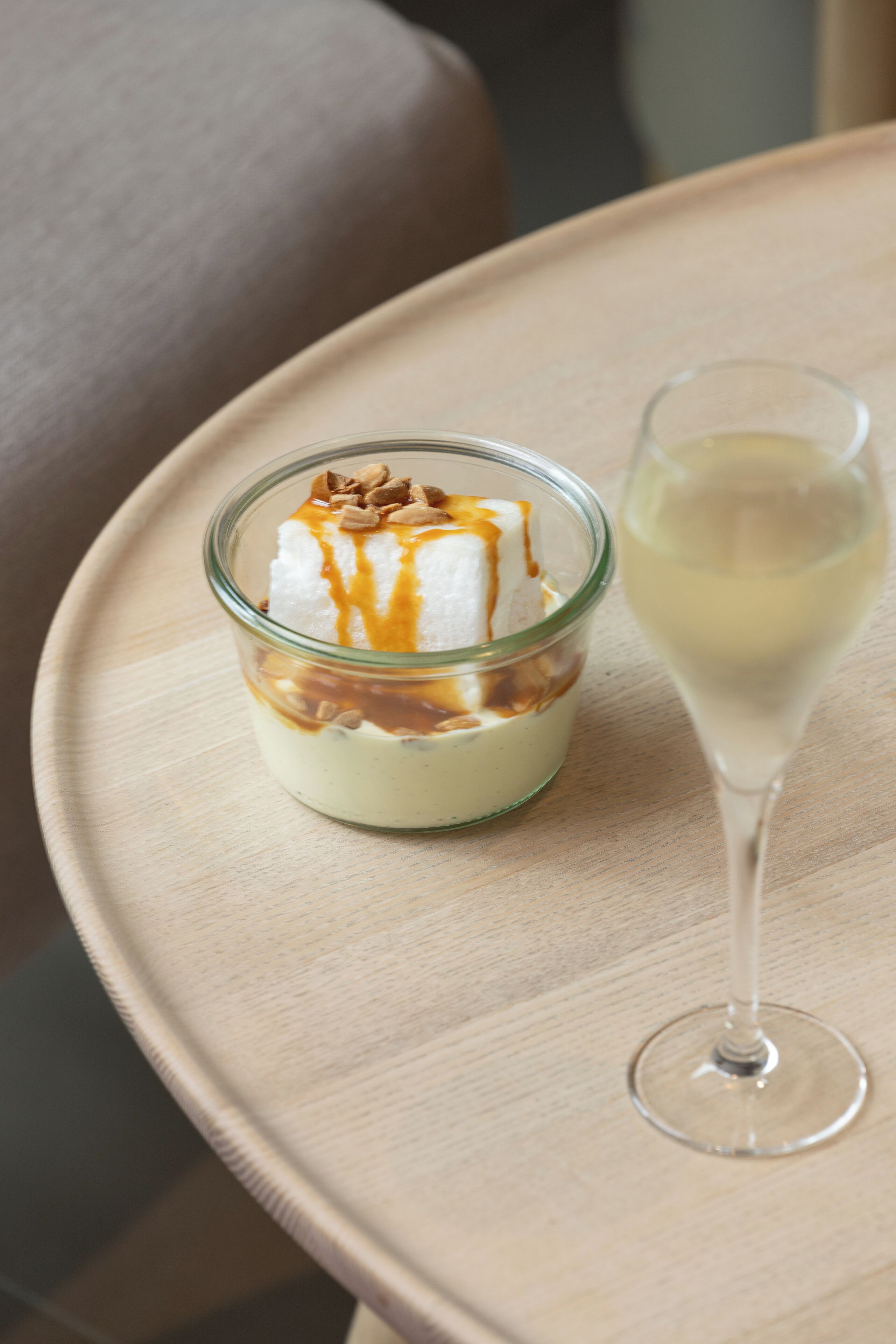 A dessert in a glass container with caramel sauce on a wooden table.
