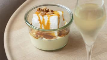 Un postre en un recipiente de vidrio con salsa de caramelo sobre una mesa de madera.