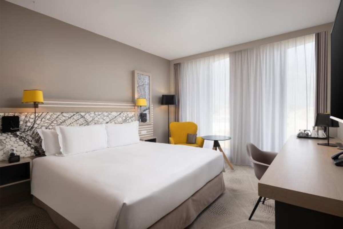 Een hotelkamer met een bed, een bureau, een stoel en een tafeltje.
