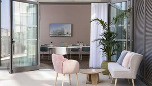 Un interior modern amb una porta de vidre que dona a una zona d'estar a l'aire lliure, un sofà, una taula petita i una planta en test.