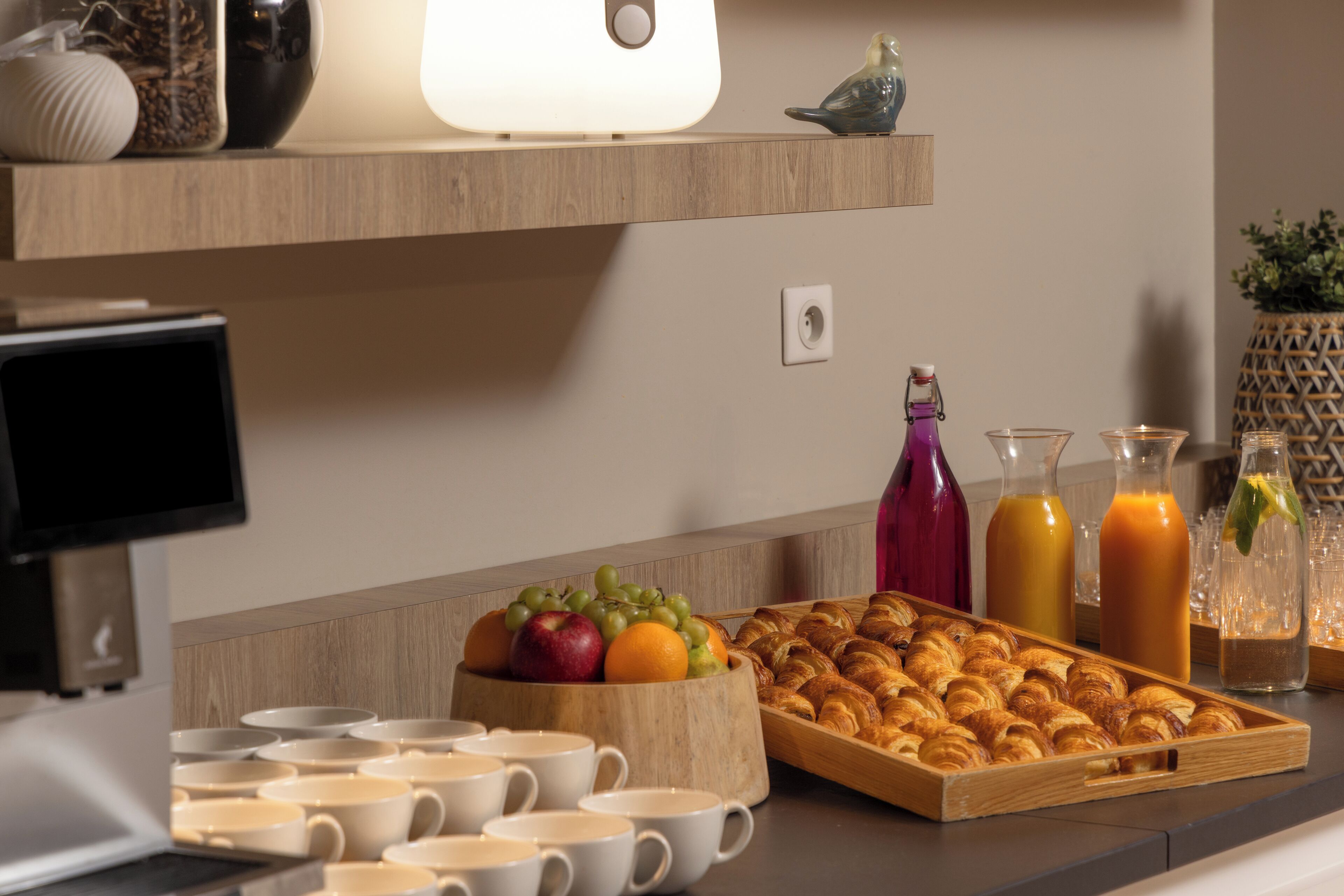 Un bufé de desayuno con frutas, pasteles y bebidas sobre una encimera de madera.