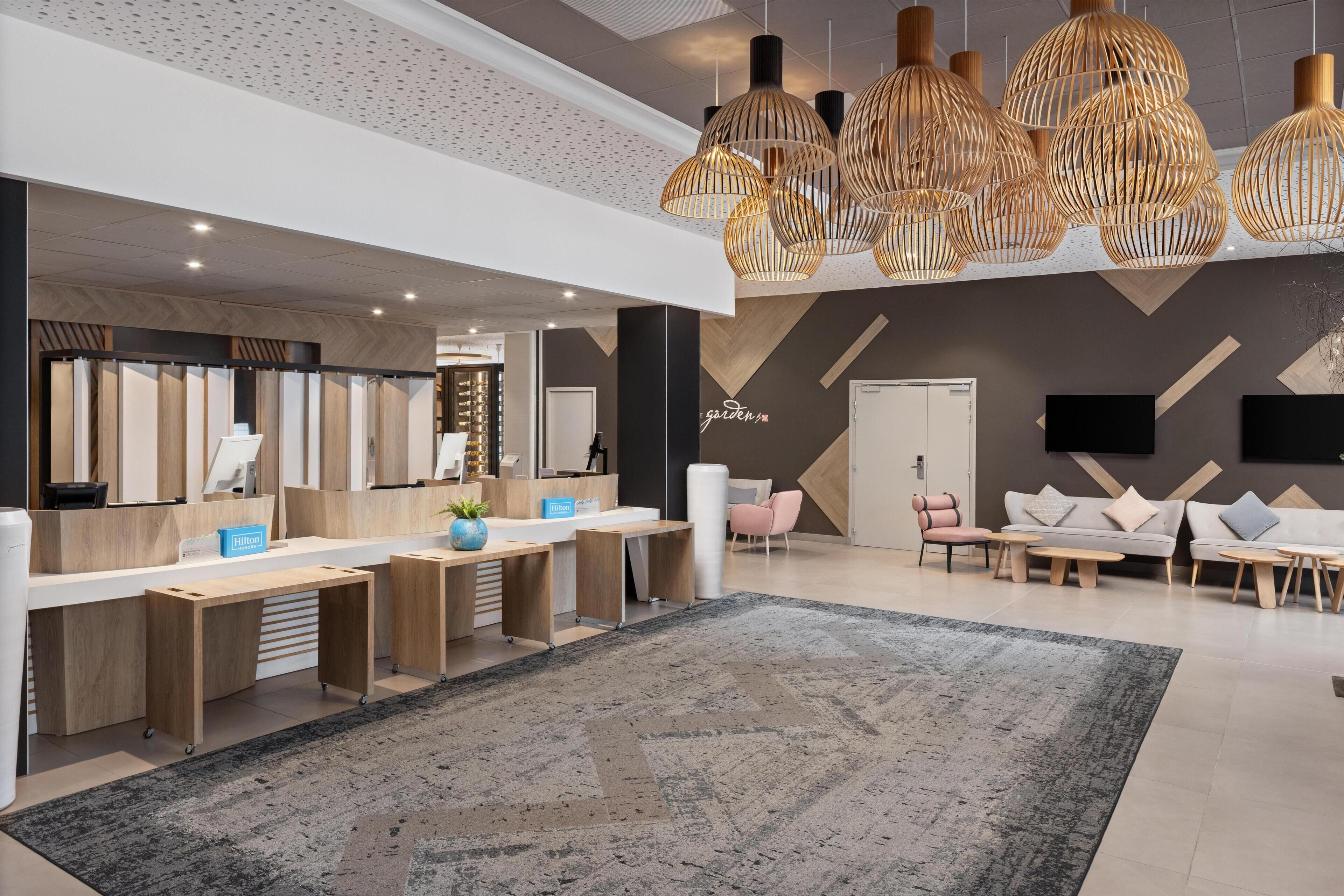 Un hall d’hôtel moderne comprenant un comptoir d’accueil, un espace salon et un éclairage décoratif.