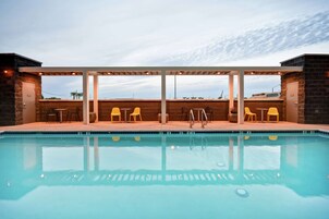 Una piscina al aire libre, sillones reclinables de piscina