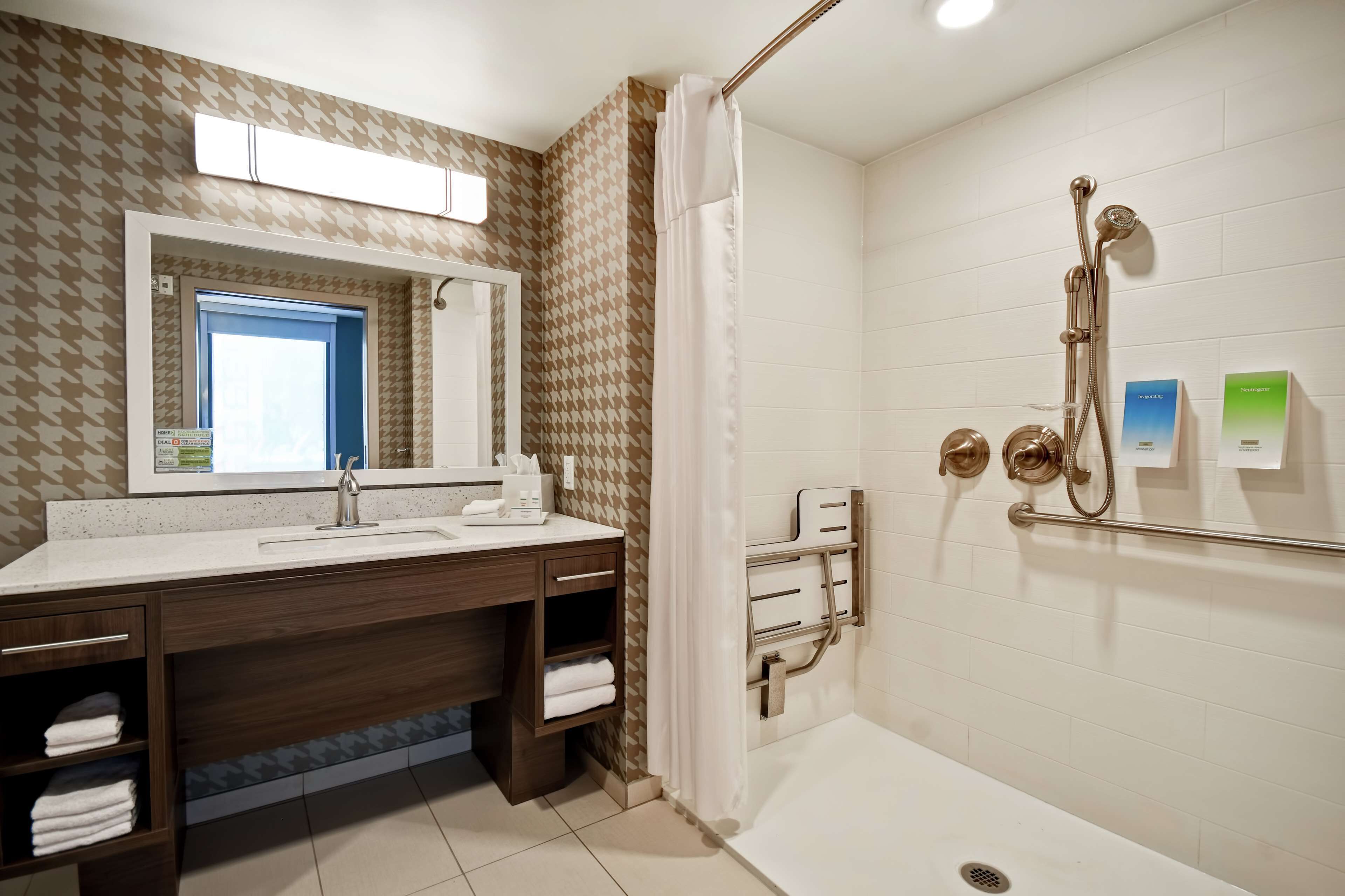 A modern bathroom with a shower, a sink with a mirror, and a towel rack.