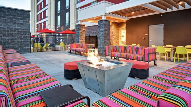 An outdoor seating area with colorful striped sofas and a fire pit. - Home2 Suites by Hilton Gilbert (Gilbert)
