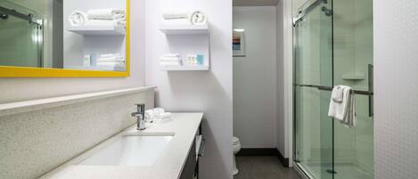 Un bagno moderno con lavandino bianco, specchio e cabina doccia in vetro.