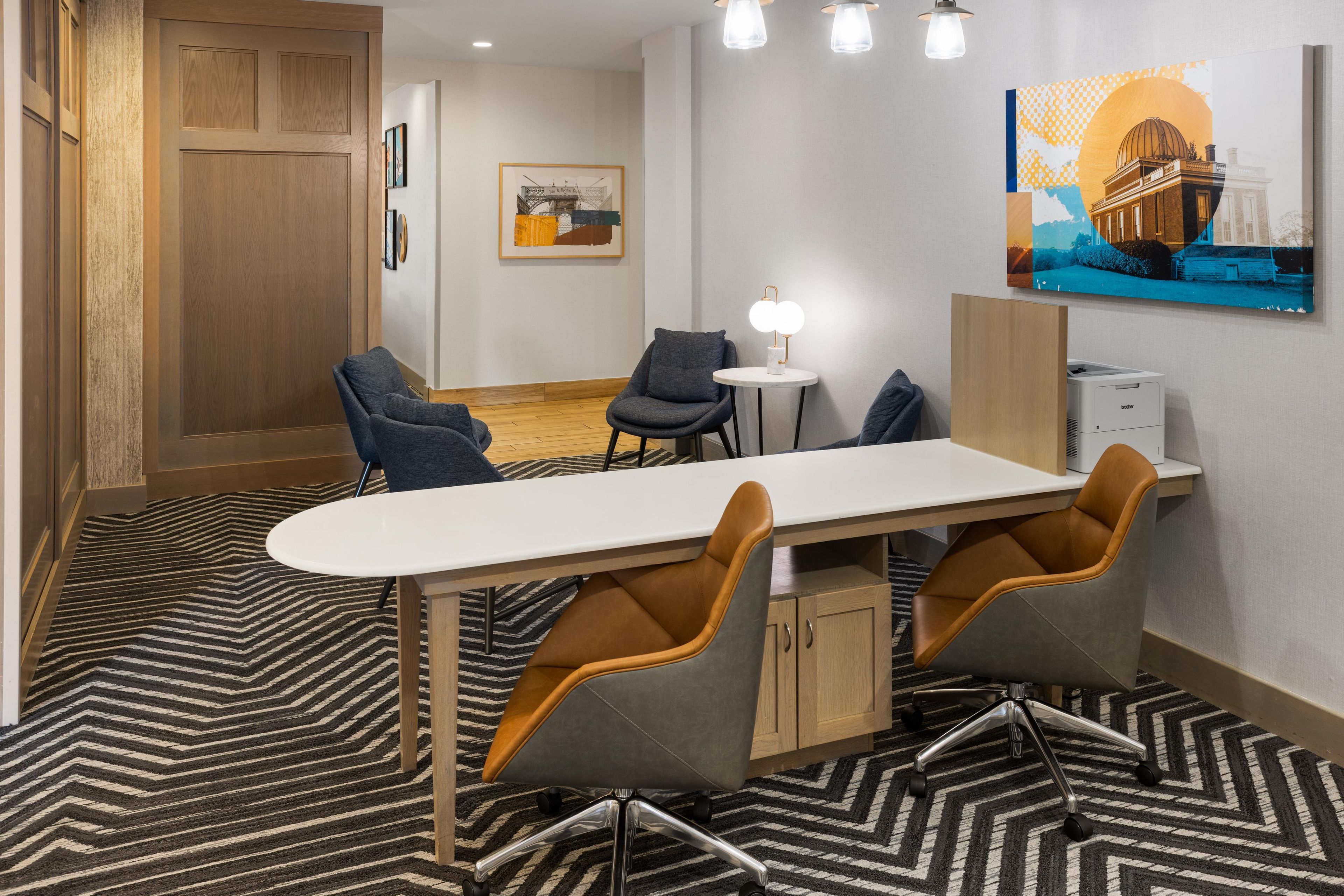 A modern meeting room with a white table, four chairs, a small round table with a lamp, and a painting on the wall.