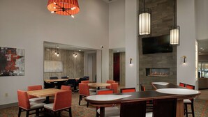 Un vestíbulo de hotel con una amplia zona de estar, chimenea e iluminación moderna.