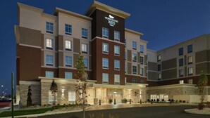 Un hotel de varios pisos con un llamativo letrero de "Homewood Suites", que presenta fachada de ladrillo y múltiples ventanas.