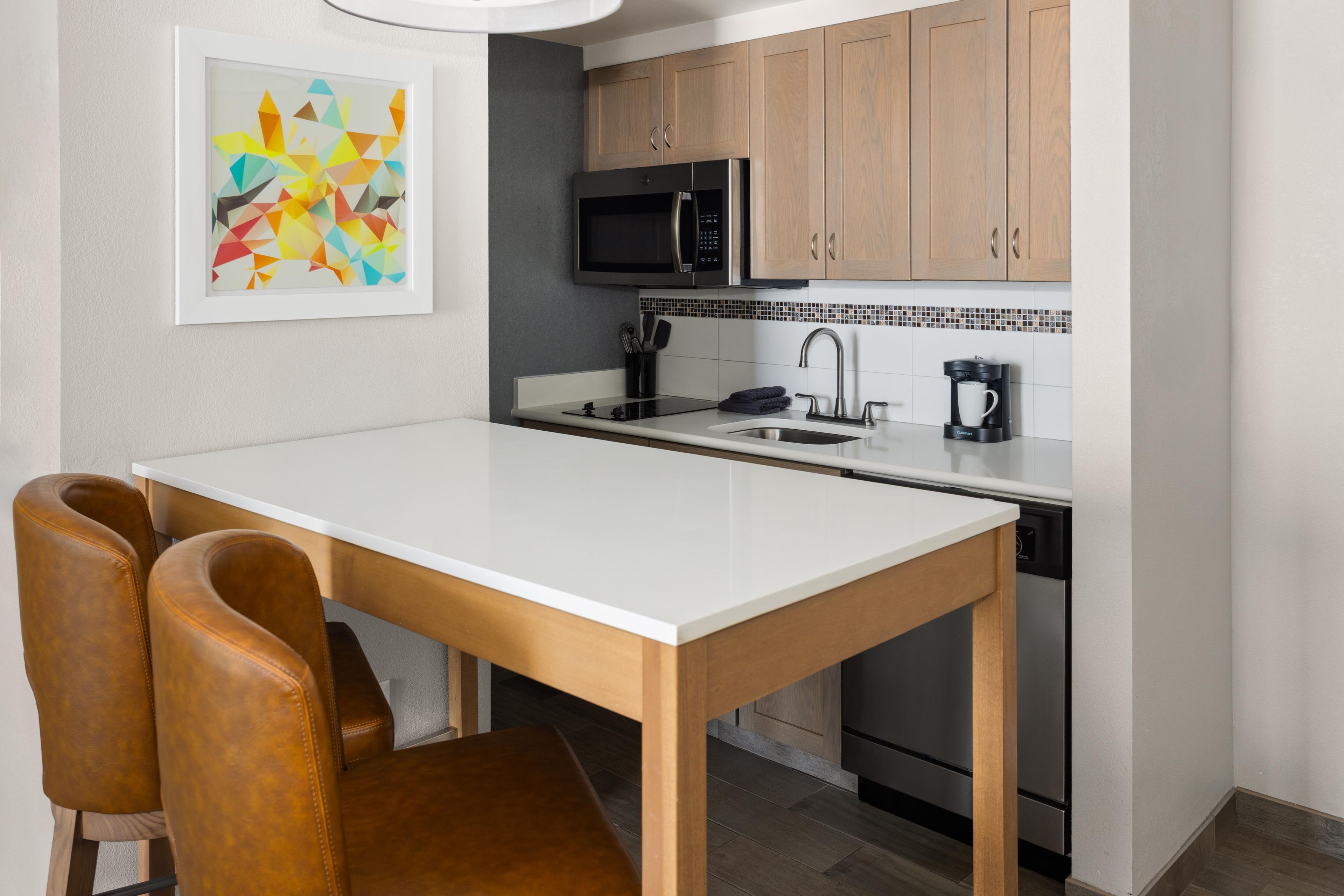 A modern kitchen with a white countertop, stainless steel appliances, and wooden cabinets.