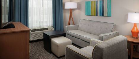 Habitación de hotel con sofá, una mesita, televisor y lámpara.
