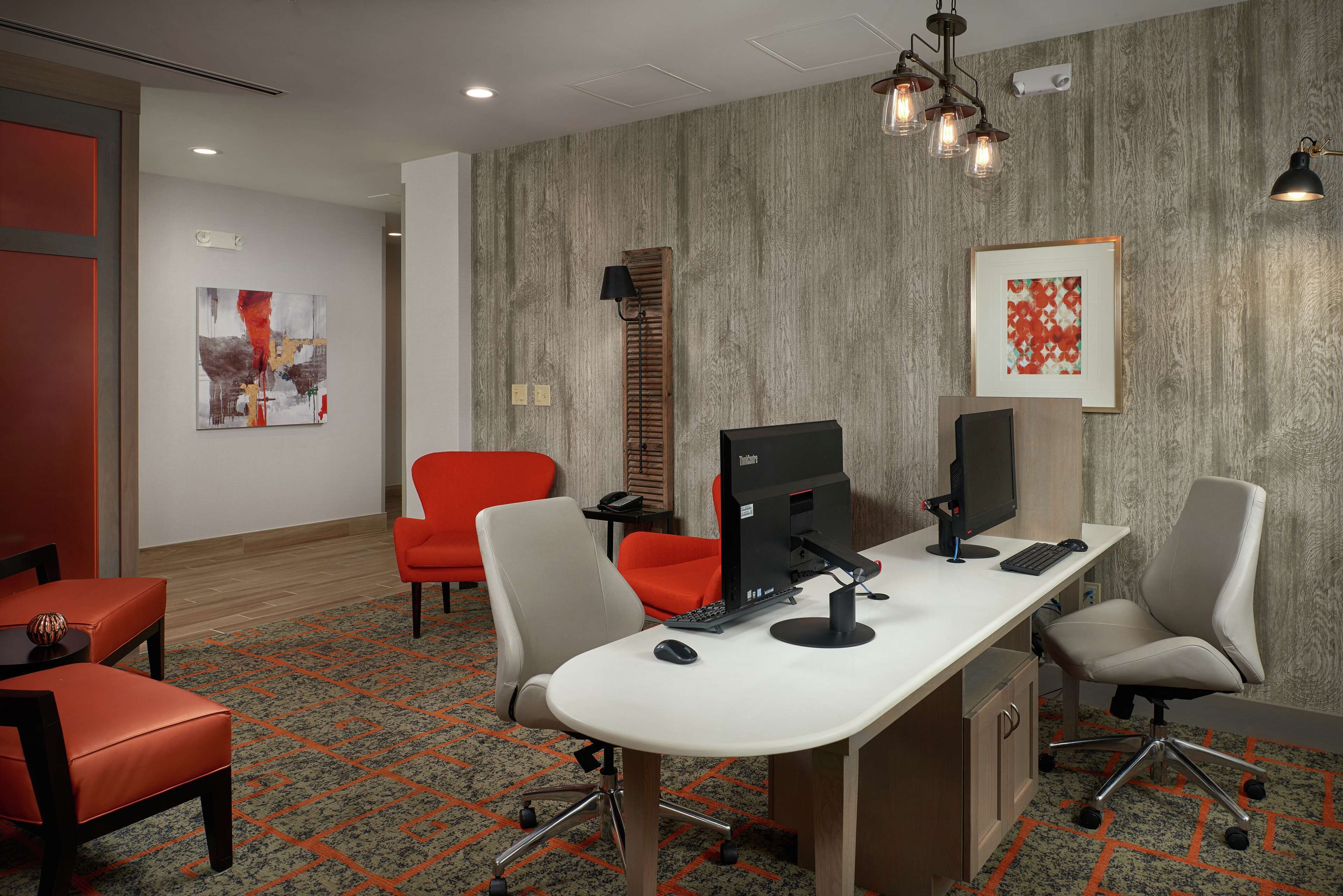 A modern office space with a white desk, two office chairs, a computer, and a lamp.