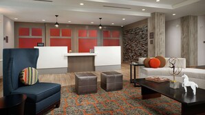 Vestíbulo de hotel con mostrador de recepción, zona de estar y una pared decorativa.