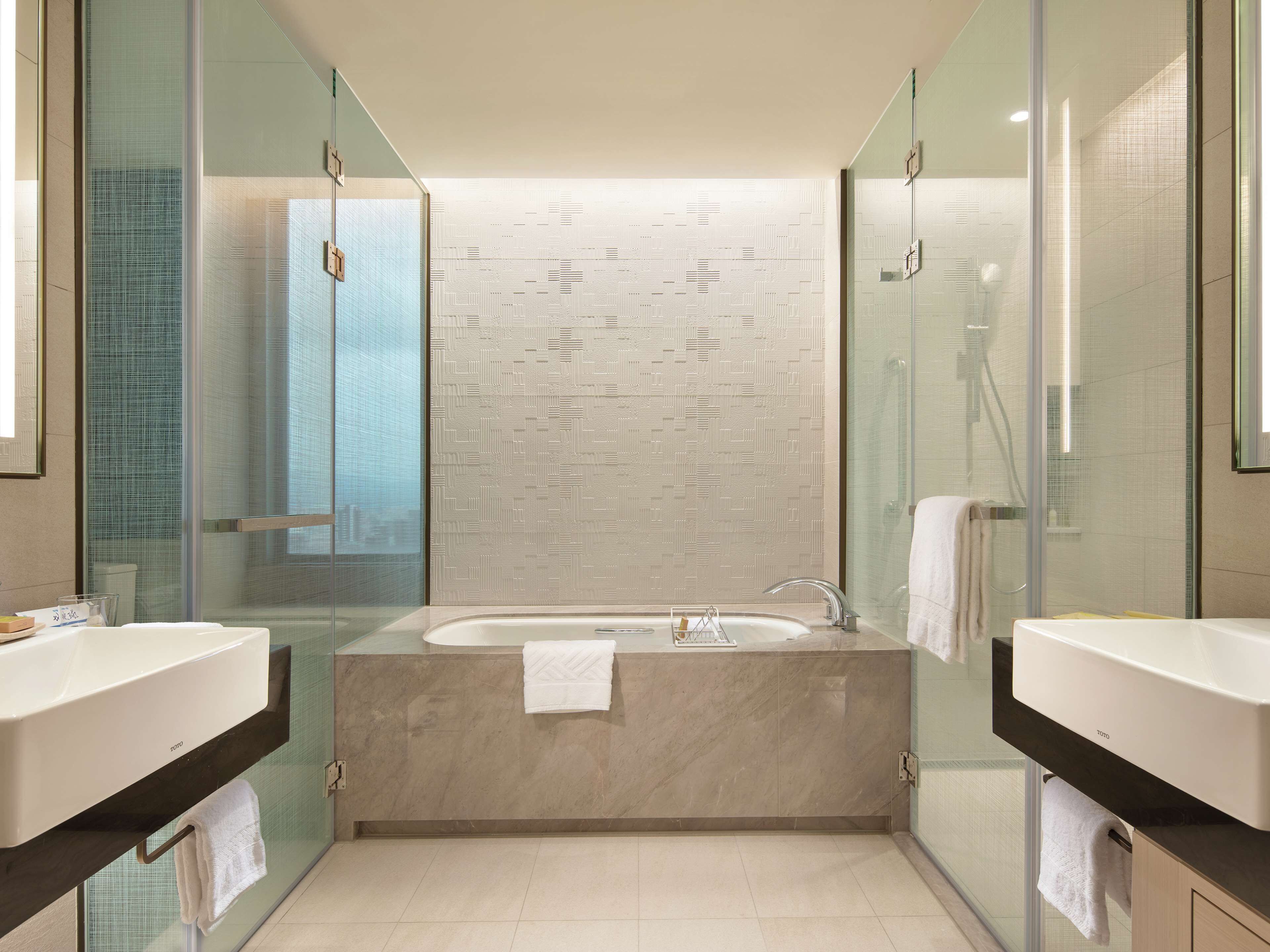 Ein modernes Badezimmer mit einer freistehenden Badewanne, zwei Waschbecken und einer Duschkabine aus Glas.