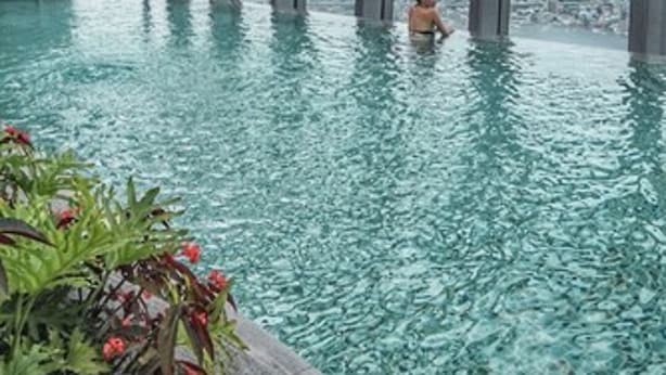 An indoor infinity pool with a city view, surrounded by a glass structure. - Hilton Taipei Sinban (New Taipei City)