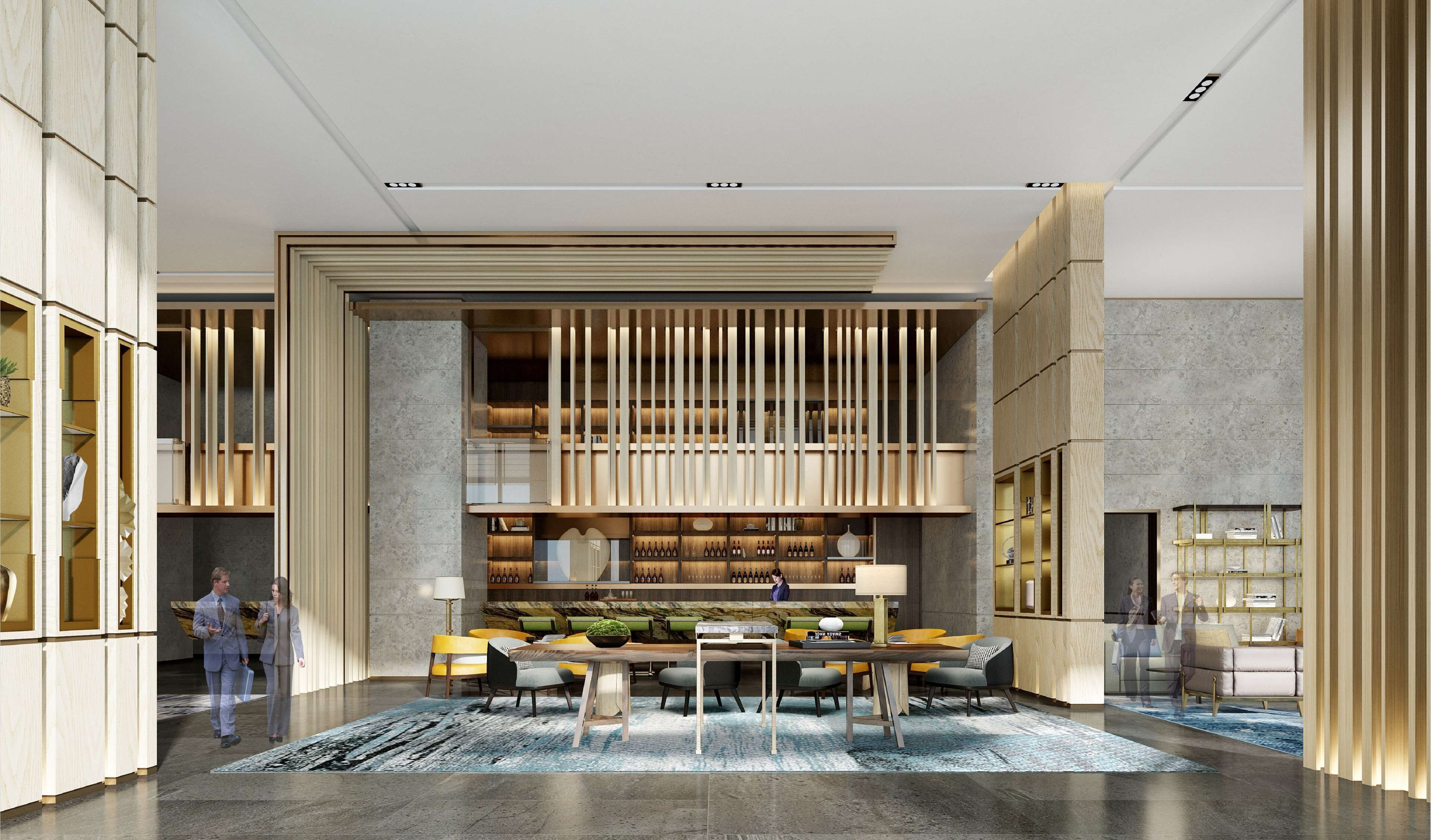 A modern interior with a central seating area, a bar, and a high ceiling with recessed lighting.