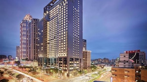A modern high-rise hotel with multiple floors, large windows, and a prominent entrance. - Hilton Taipei Sinban (New Taipei City)