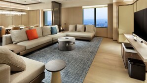 A modern living room with a sectional sofa, a round coffee table, and a flat-screen TV. - Hilton Taipei Sinban (New Taipei City)